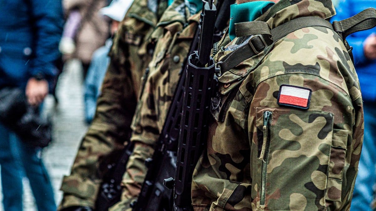 Close-up of Polish soldiers in camouflaged uniforms standing in line during a public event.