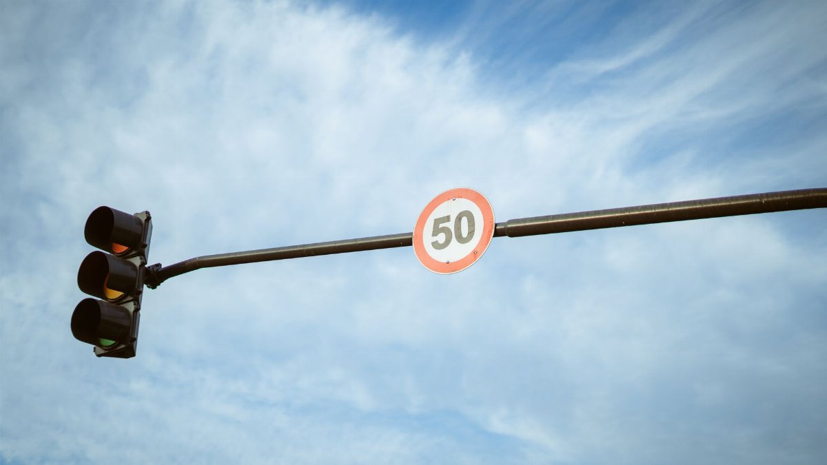 A traffic light and speed limit sign under a blue sky in Buenos Aires, Argentina.