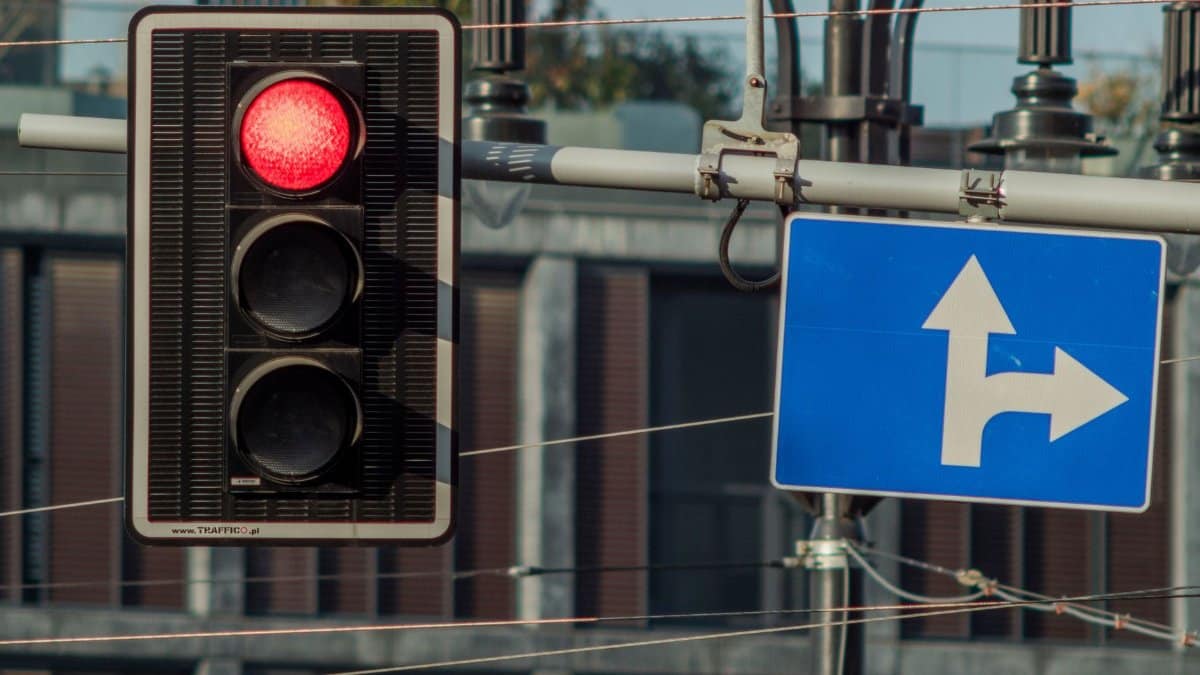 Red traffic light and directional road sign in Wrocław, Poland.