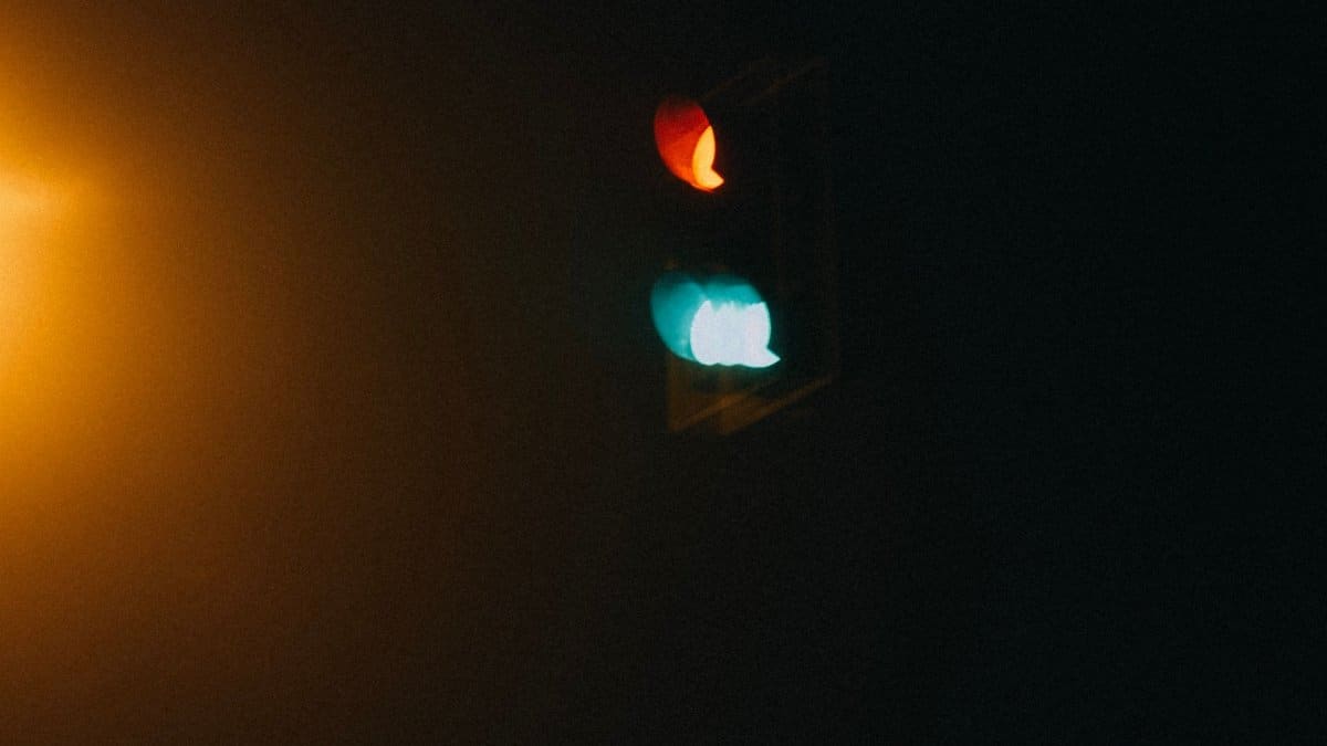 Artistic shot of blurred red and green traffic light glowing in the night, with a moody and dramatic tone.