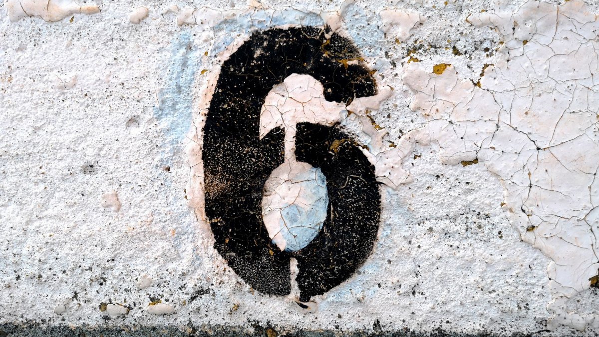 Close-up of a weathered number six painted on a cracked road surface.