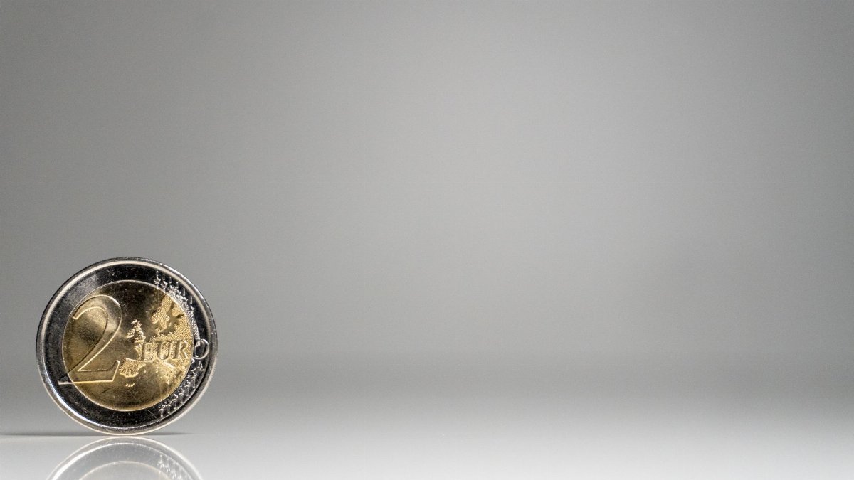 A detailed image of a 2 Euro coin on a reflective surface with ample copy space.