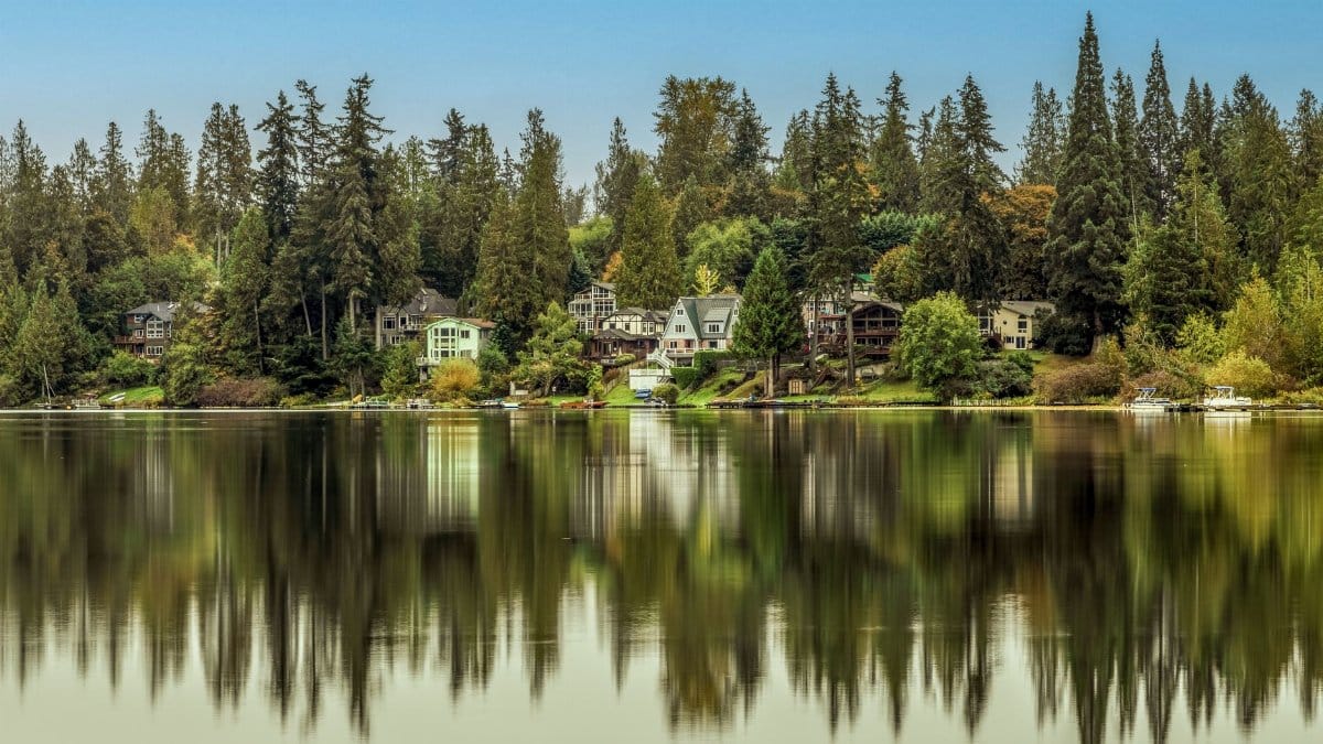 Scenic view of lakefront homes and evergreen trees reflecting in calm waters of Renton, WA.
