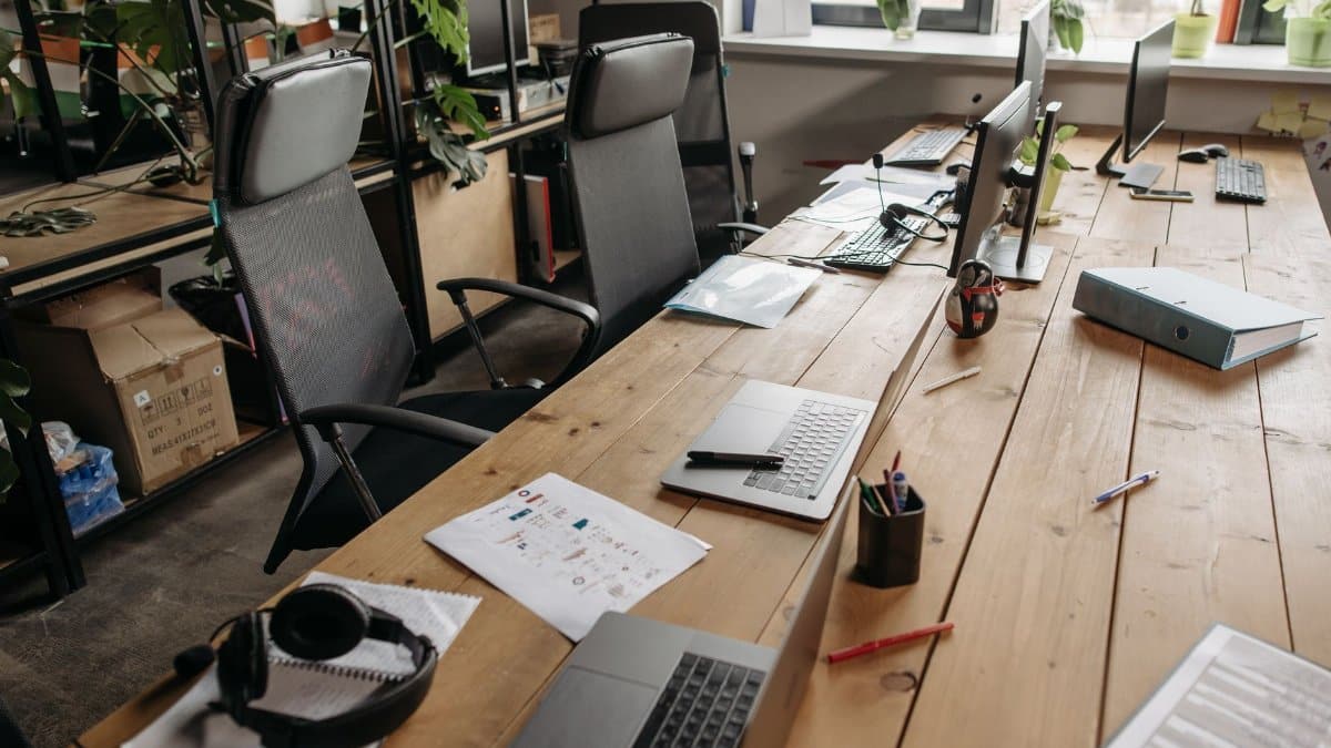 Spacious co-working office with wooden desks, laptops, and modern chairs.