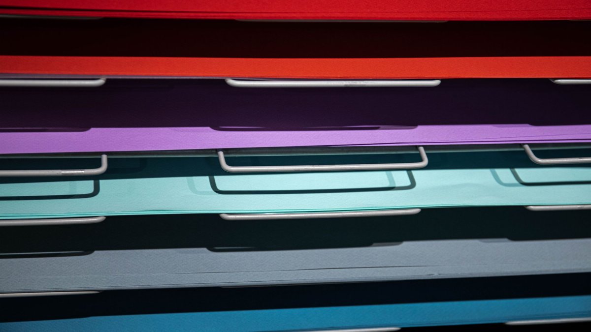 Stacked colorful papers in an art studio, perfect for craft projects.