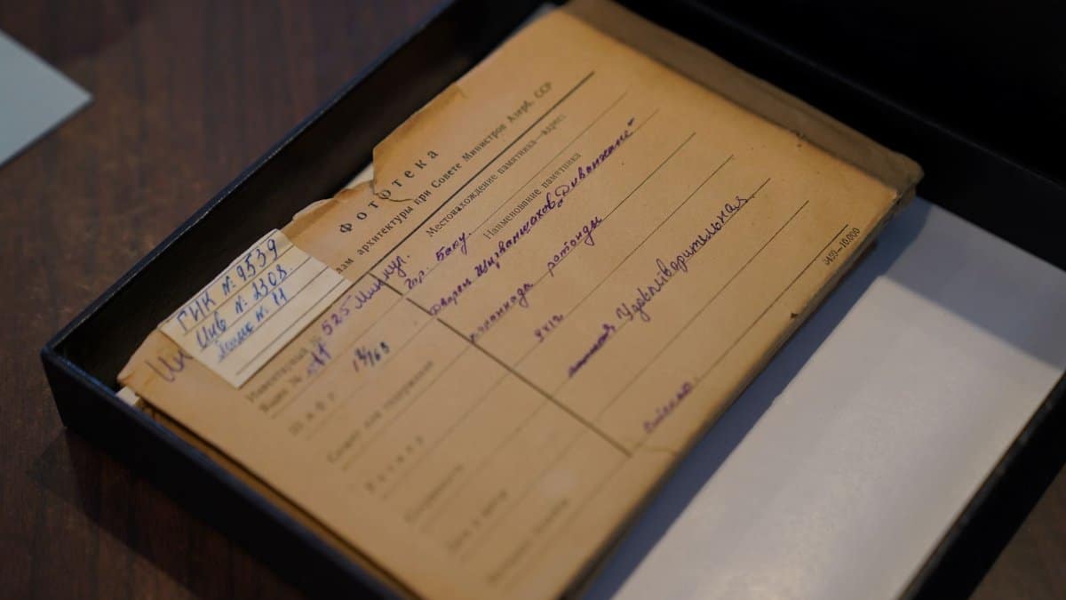 An old Russian document placed inside an archive box on a wooden desk.