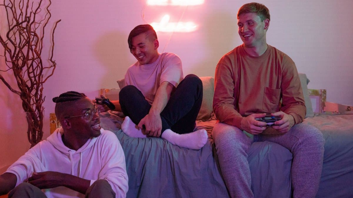 Three diverse friends joyfully playing video games together in a cozy room setting.