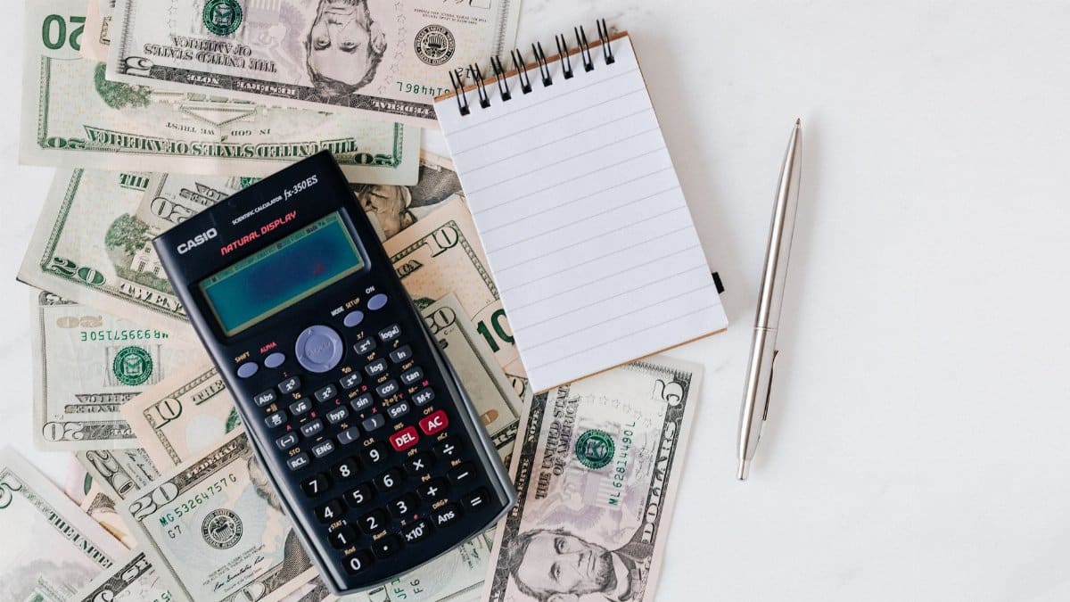 Top view of electronic calculator and notepad placed over United States dollar cash money together with metallic pen for budget planning and calculation