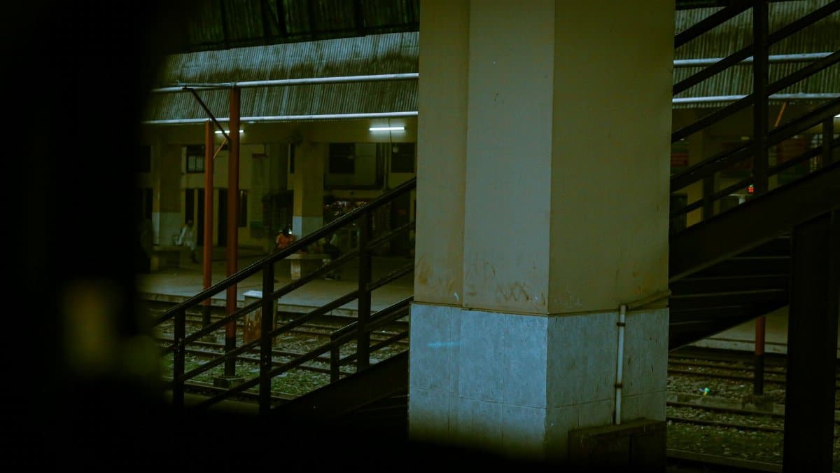 Moody view of a dimly lit train station with stairs leading to the tracks.