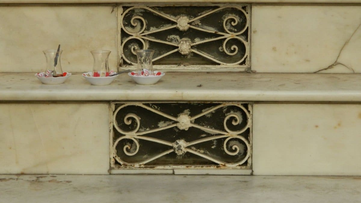 Marble steps adorned with empty Turkish tea glasses and intricate vintage grating.