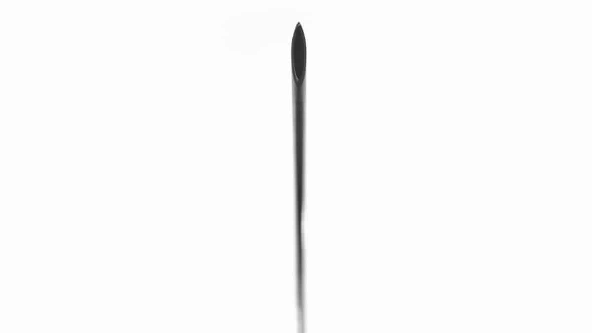 Close-up of a hypodermic needle's sharp point against a white background.