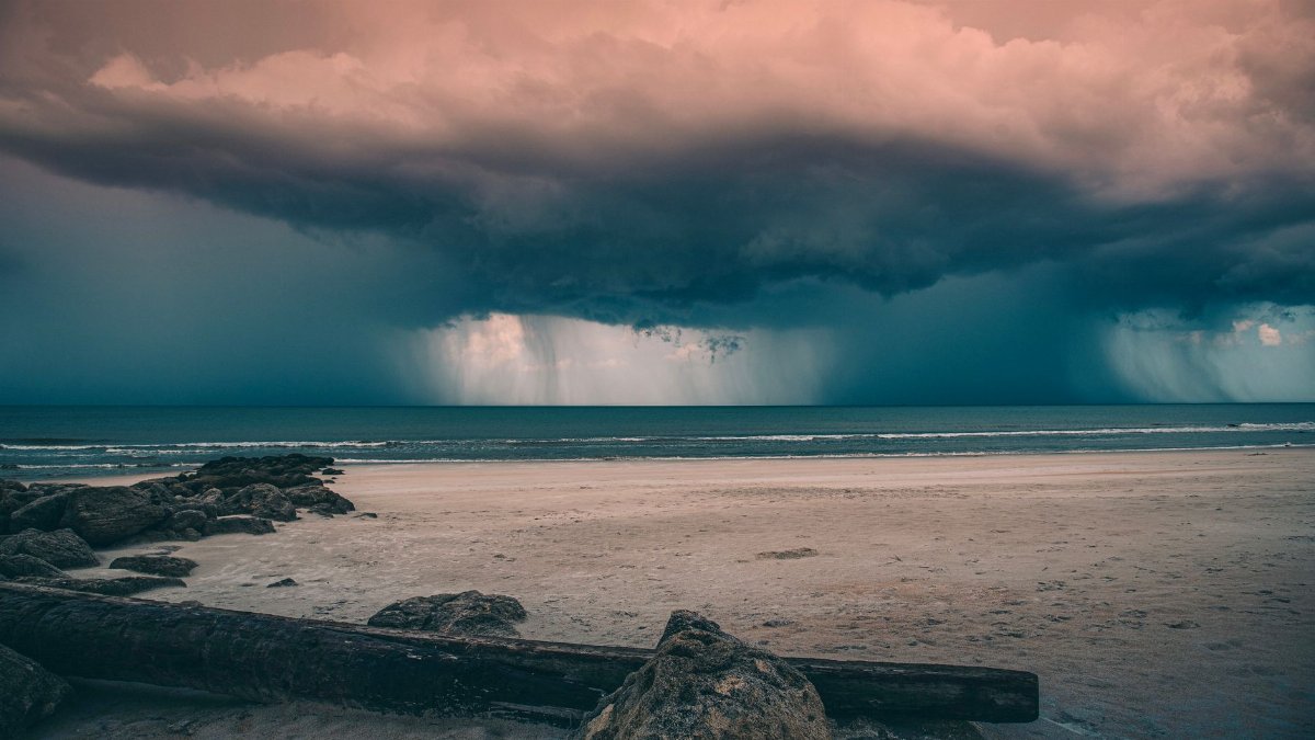Powerful storm clouds loom over a serene beach, capturing nature's drama and tranquility.