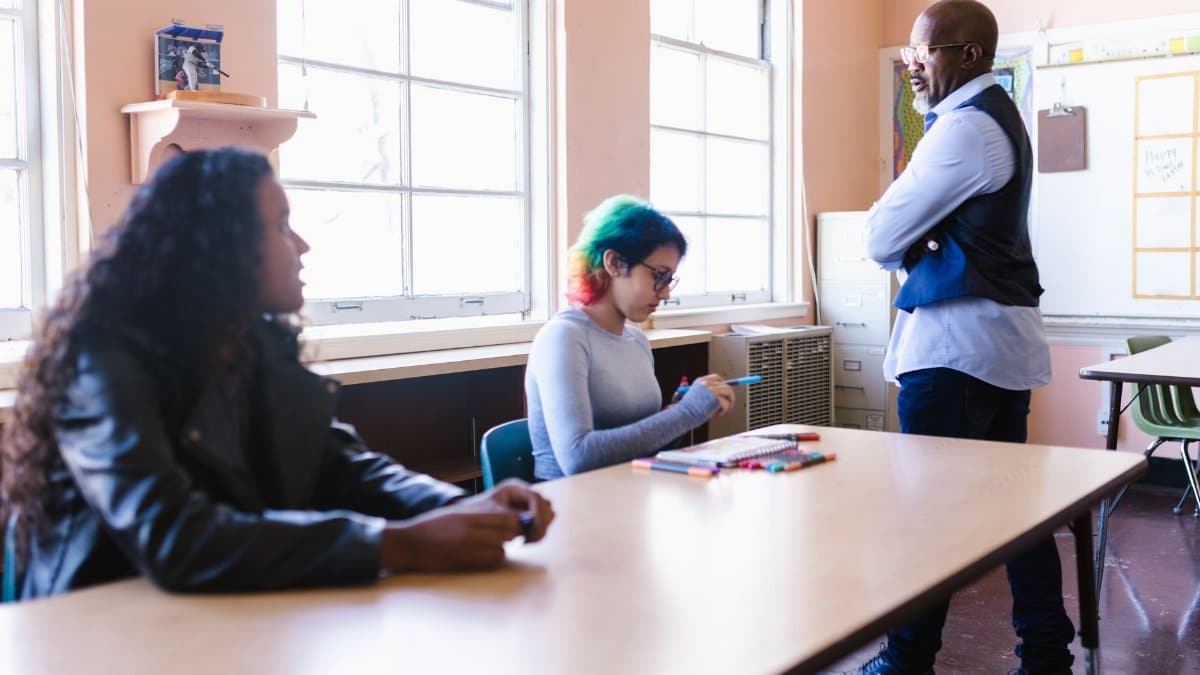 Teacher and students engaged in a classroom discussion with natural light.