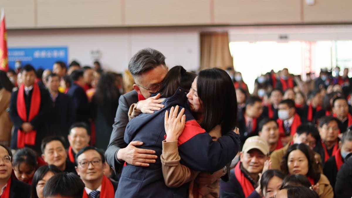 Joyous moment as families embrace at a graduation ceremony indoors.