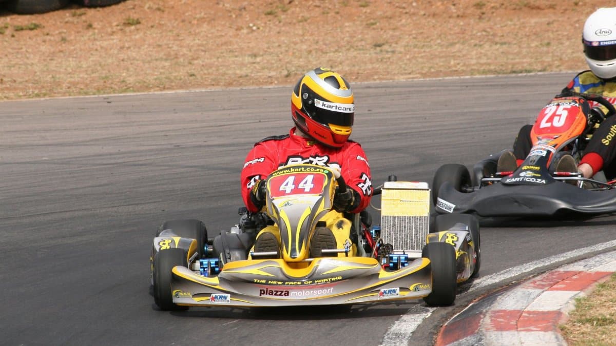 Competitive go-karts turn a sharp corner on a motorsport track, showcasing speed and agility.