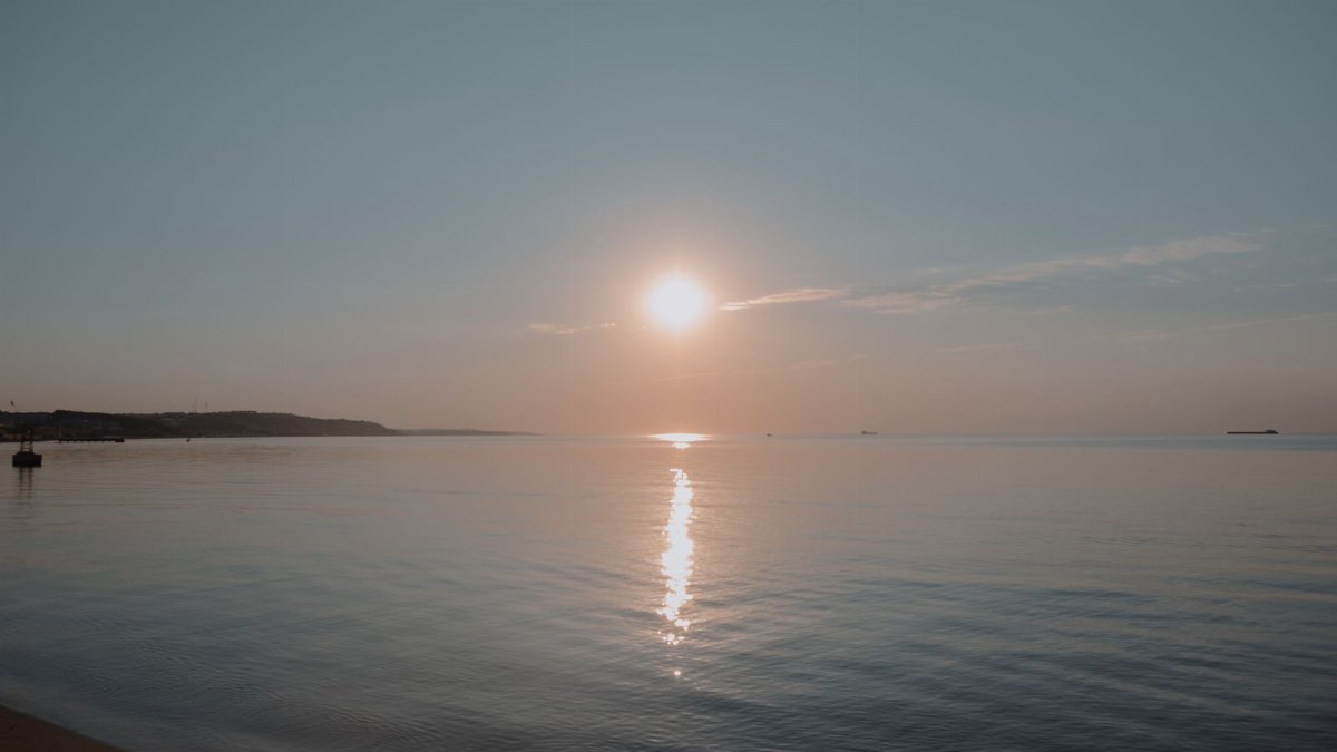 Peaceful sunrise over a calm ocean with a clear sky, perfect for relaxation and contemplation.