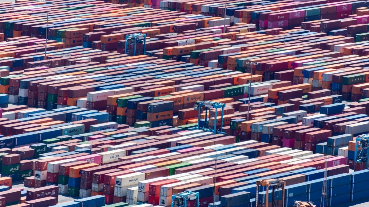 Colorful shipping containers stacked at a busy port, aerial view.