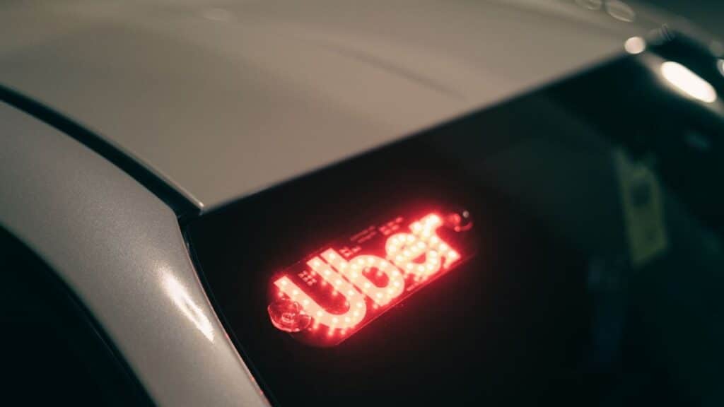 Close-up of a ride-sharing car with a bright red illuminated sign for night-time travel.