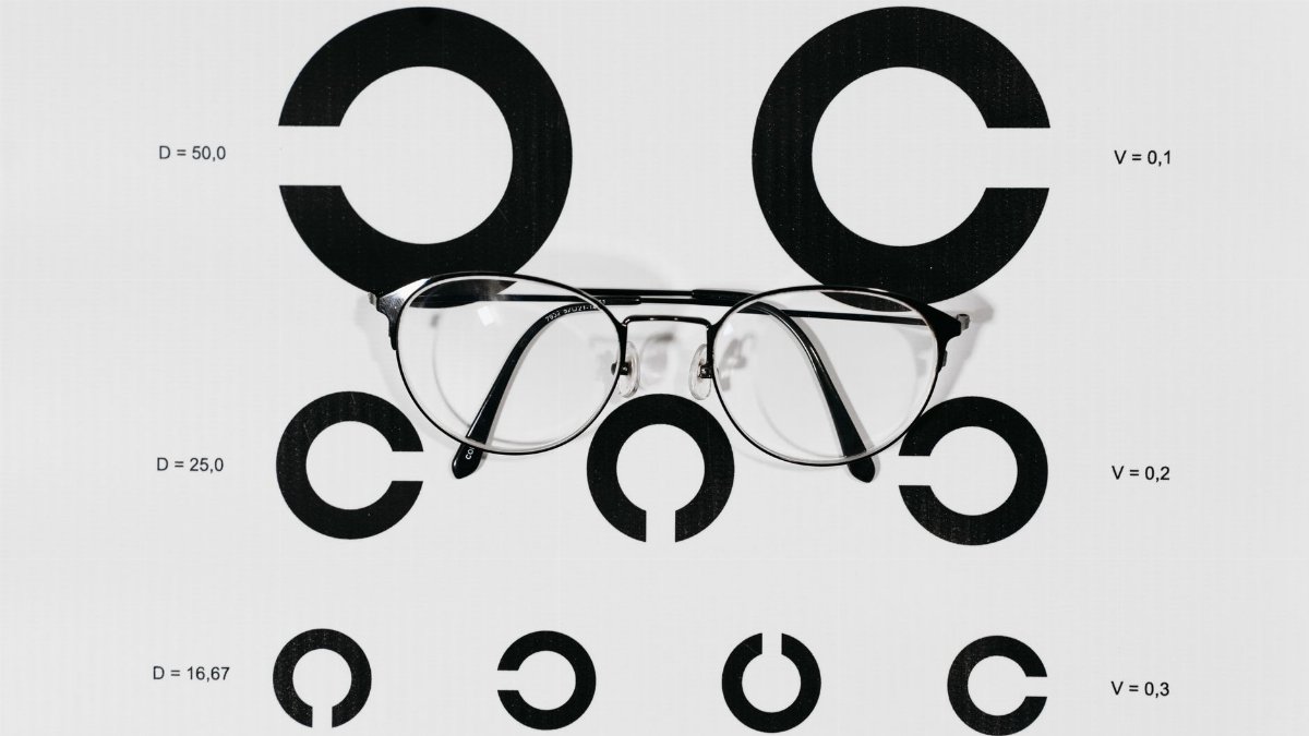 A close-up view of eyeglasses placed on a Snellen chart used for vision testing.