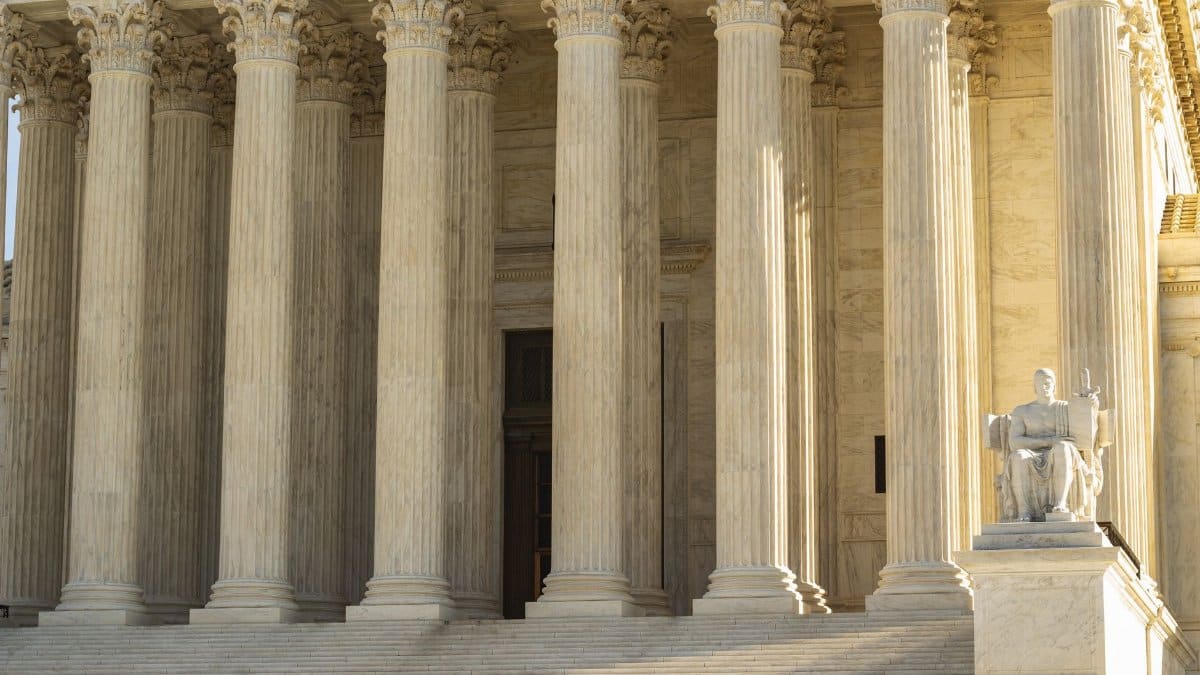 The Supreme Court of the United States with iconic marble columns and statue, captured in natural light.