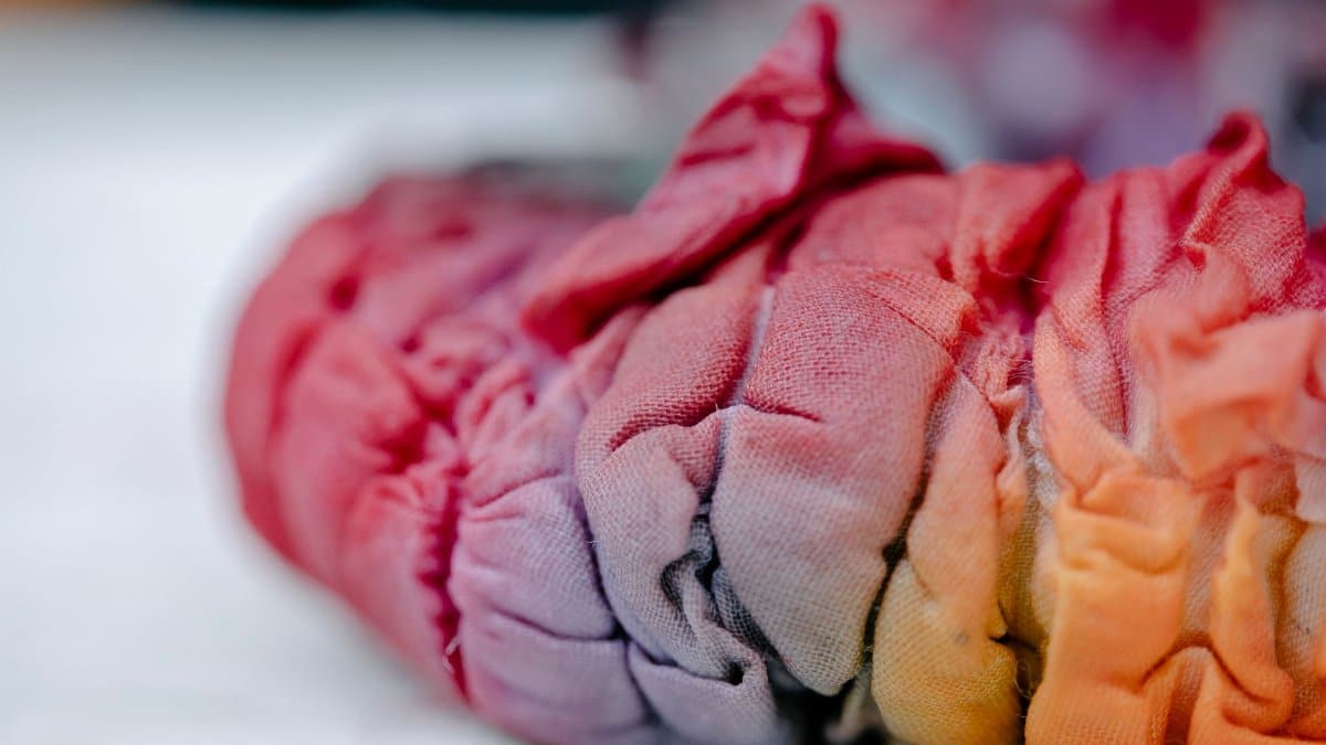 Focused shot of colorful, creased tie-dye fabric, showcasing its vibrant spectrum and texture.