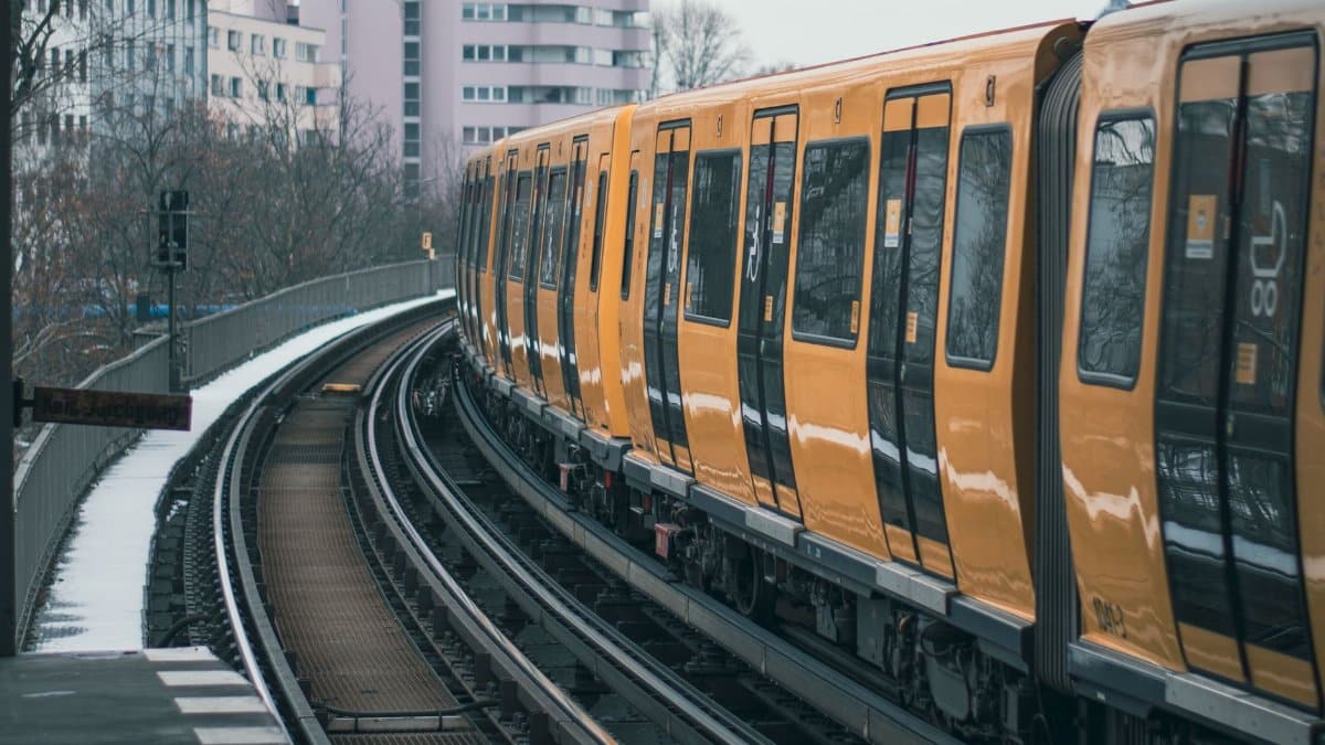 A yellow train moving along urban tracks amidst city buildings, showcasing public transit.
