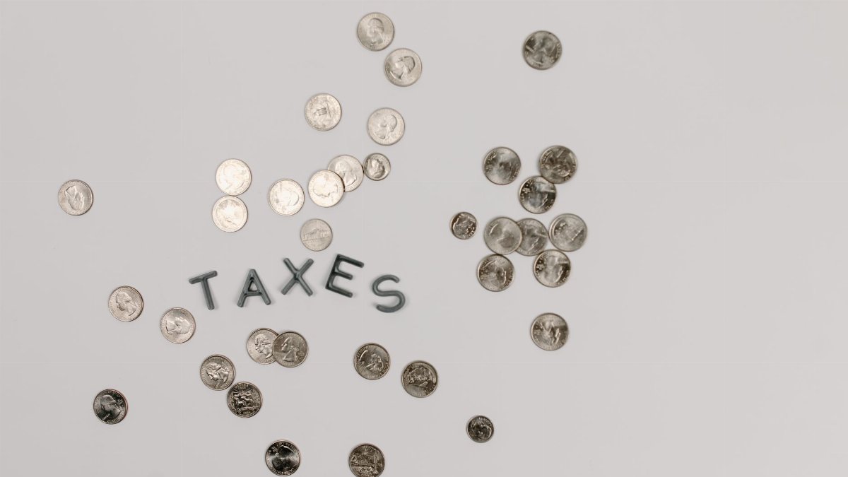 A visually striking flatlay of coins with 'Taxes' text on a white surface, ideal for financial concepts.