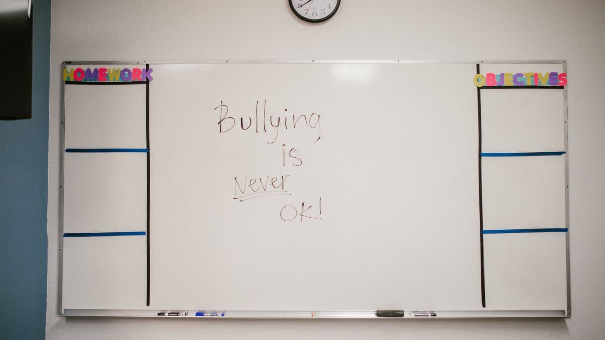 Whiteboard in classroom with 'Bullying is Never OK' message promoting awareness.