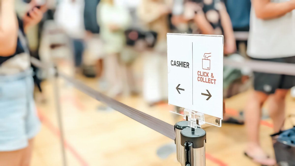 Blurred indoor scene showing a queue with a click and collect sign.