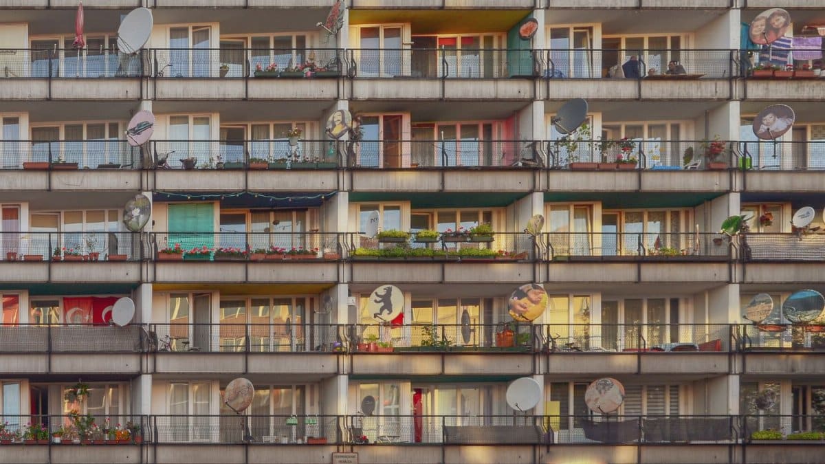 Photograph of a residential building with colorful balconies and satellite dishes in Berlin.