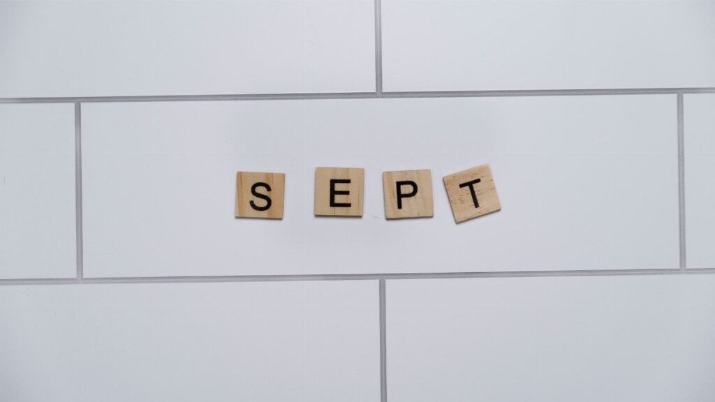 Wooden letter tiles spelling 'Sept' on a white tiled background, perfect for marking calendar events.