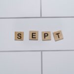 Wooden letter tiles spelling 'Sept' on a white tiled background, perfect for marking calendar events.