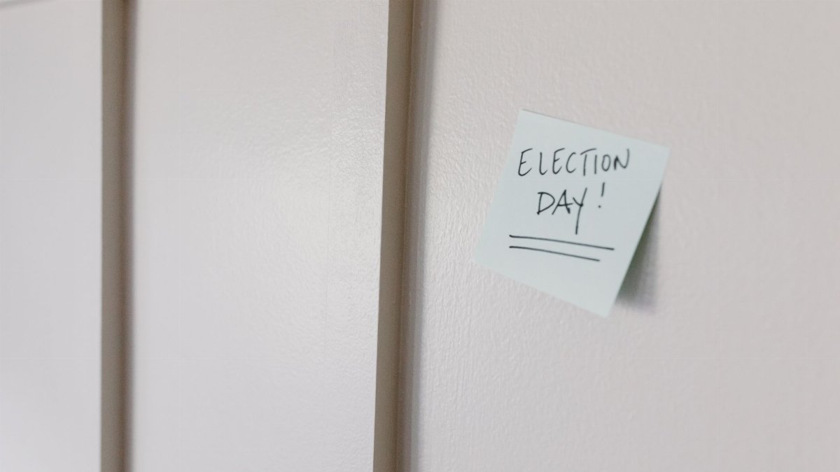 A sticky note with 'Election Day!' message on a white surface.