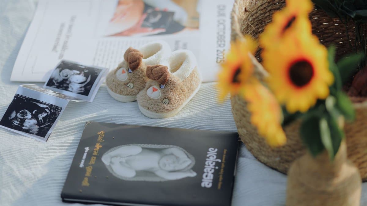 Flat lay of baby shoes, sonogram, and sunflowers, symbolizing pregnancy announcement.