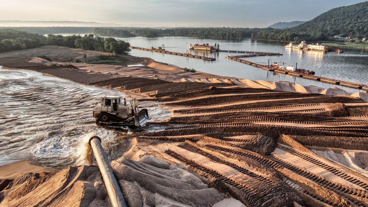 Aerial view of bulldozer at Reads Landing with a lake backdrop, highlighting industrial and natural beauty.