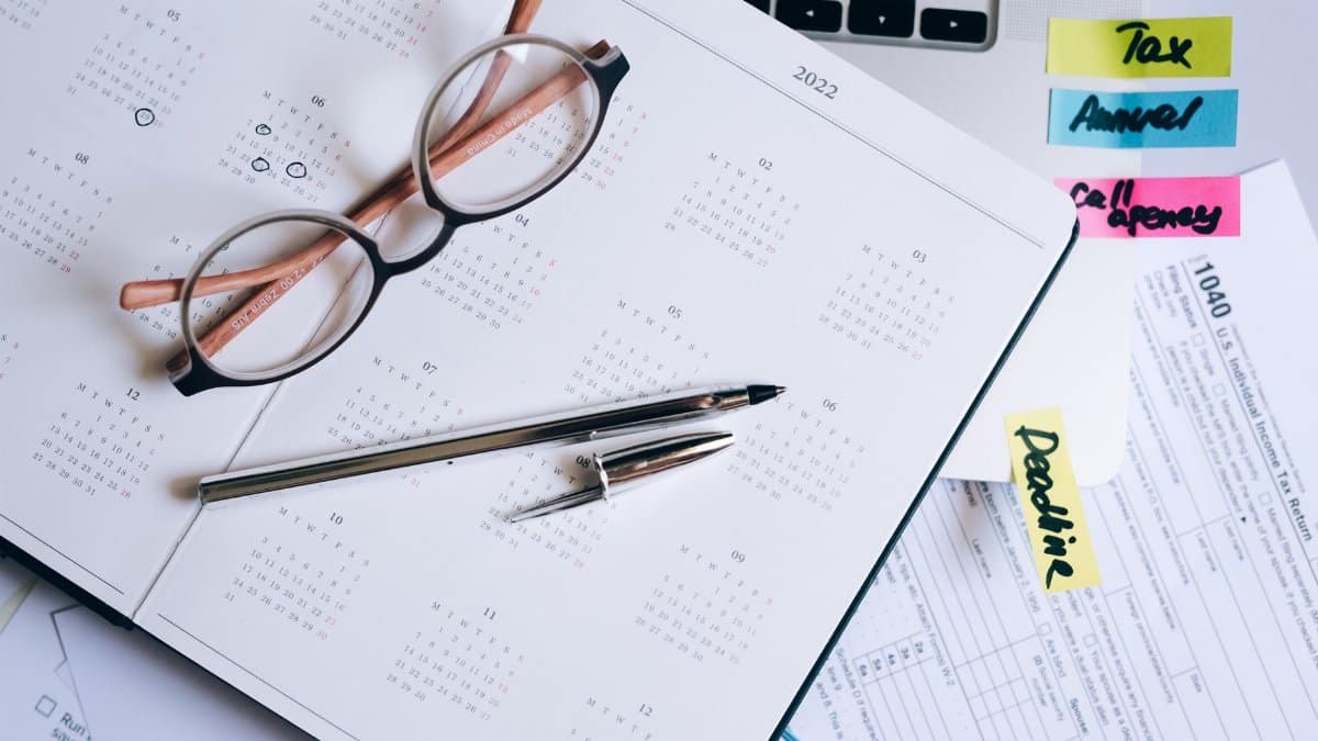 Overhead view of a desk with glasses, a pen, calendar, and tax documents.