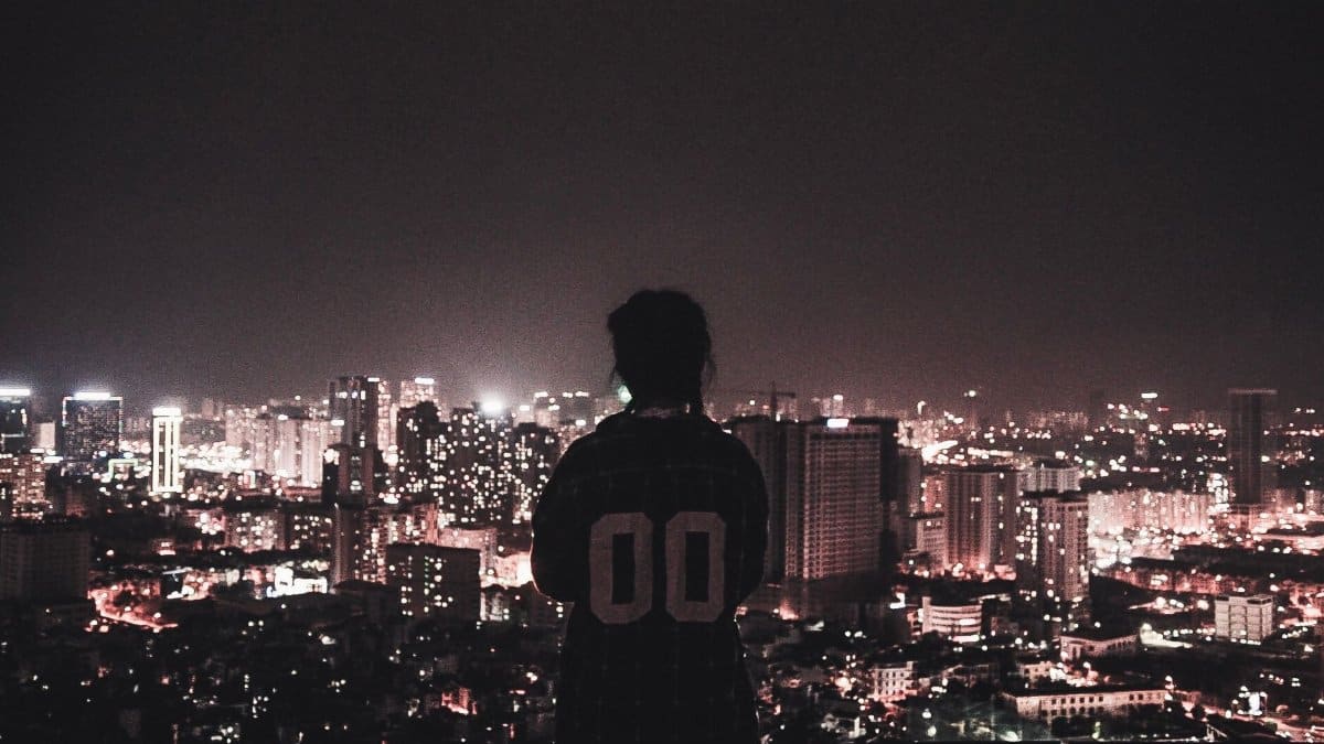 Silhouette of a person overlooking Hà Nội's city lights at night, showcasing the urban skyline.