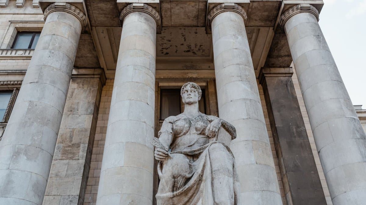 Majestic neoclassical building facade with statue and pillars, photographed in daylight.