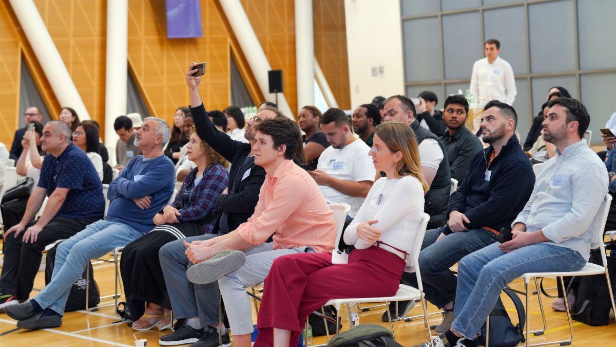 A diverse audience attentively listens during an indoor seminar, showcasing a collaborative learning environment.