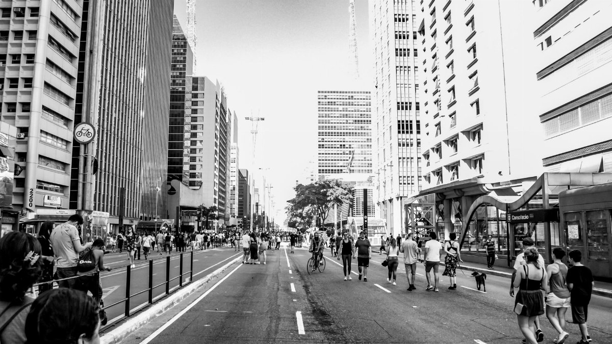 Bustling urban scene on Paulista Avenue, São Paulo, featuring people and skyscrapers in black and white.