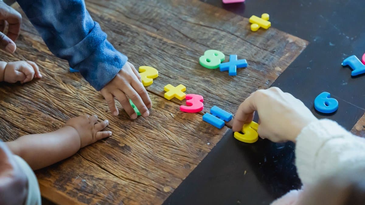 Kids engaging with colorful plastic numbers on a wooden table, fostering early math skills.