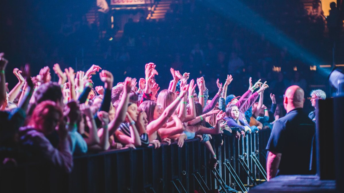 Excited crowd with hands up at a vibrant live music concert indoors.