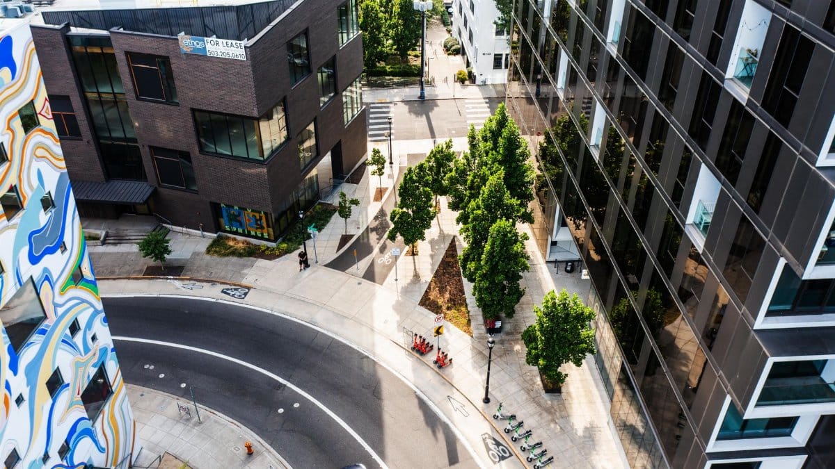 Aerial view of a city street with modern architecture and green spaces, reflecting urban planning.