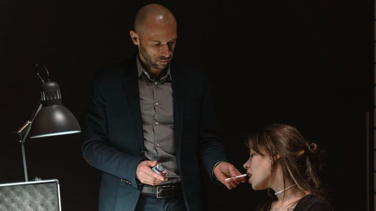 Intense interrogation scene featuring a man and woman under a dim light.