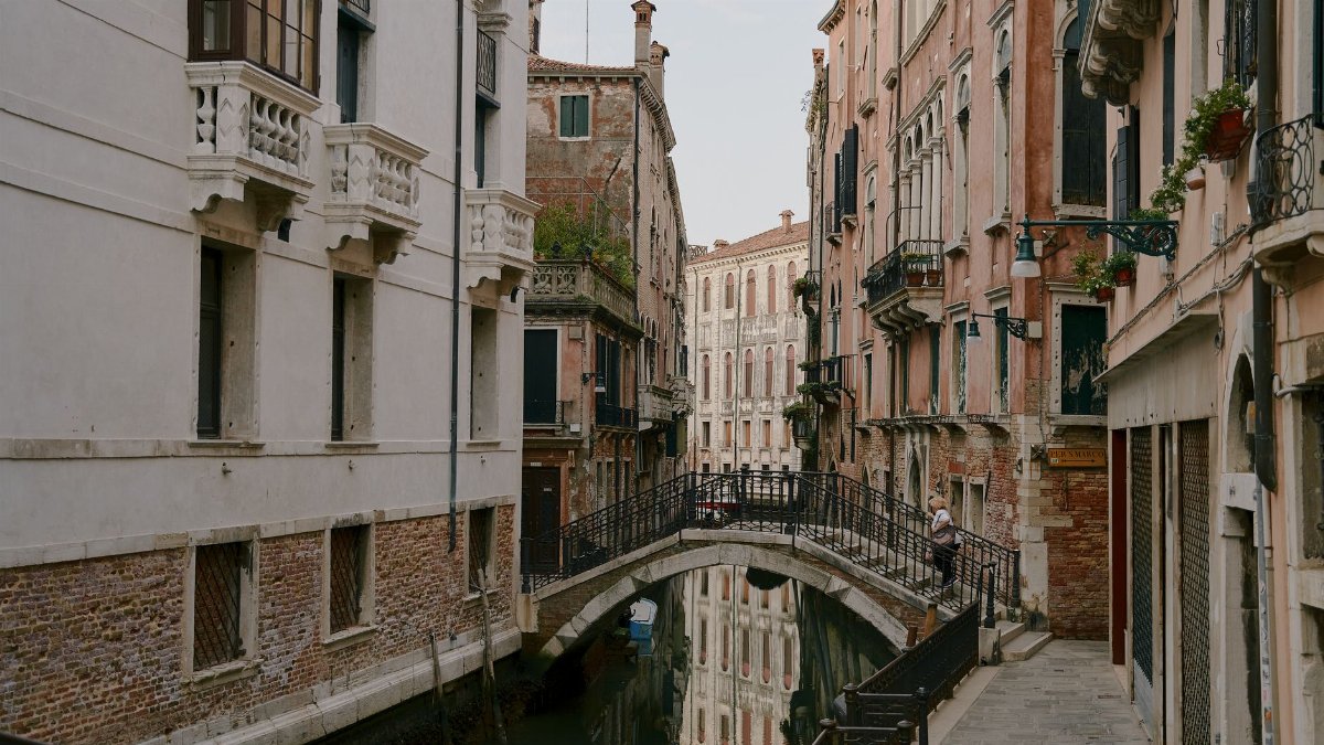 Explore the architectural beauty of a Venetian canal with charming bridges and historical buildings.