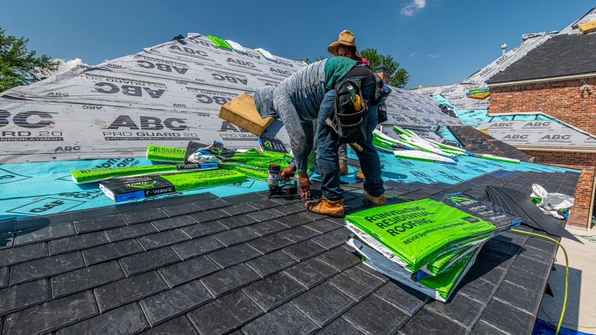 Workers installing a synthetic slate roof on a brick house in Fort Worth, Texas.