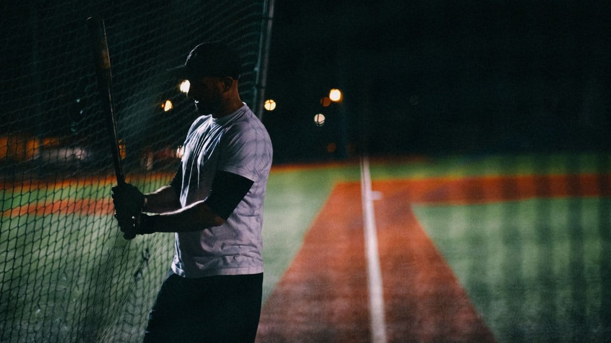 Silhouette of baseball player practicing batting at night on the field.