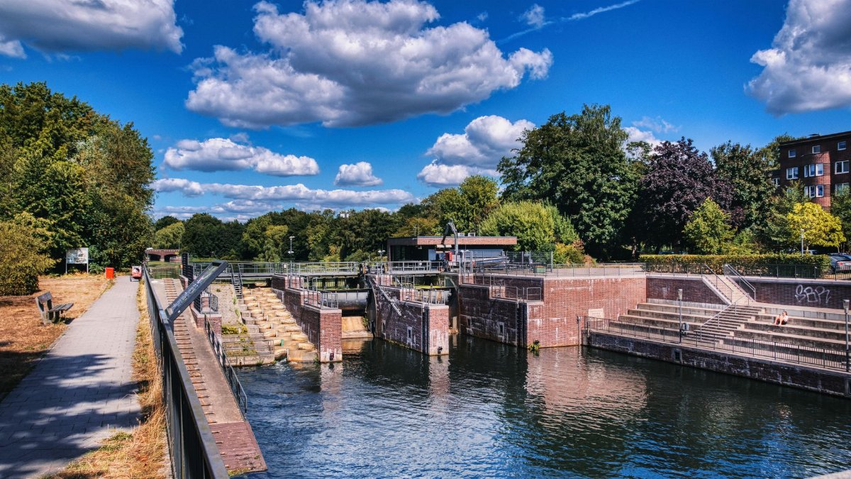 A serene urban canal with lush summer trees under a bright blue sky. Ideal for travel and nature themes.