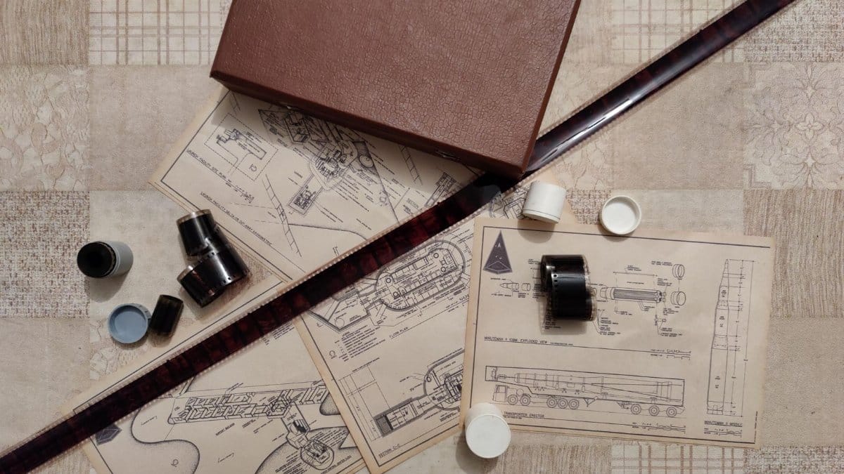 A retro-style flat lay featuring a brown leather box, blueprints, and film rolls.