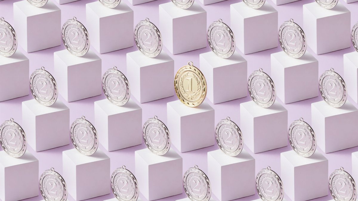 A gold medal stands out among silver medals on white cubes, showcasing uniqueness.